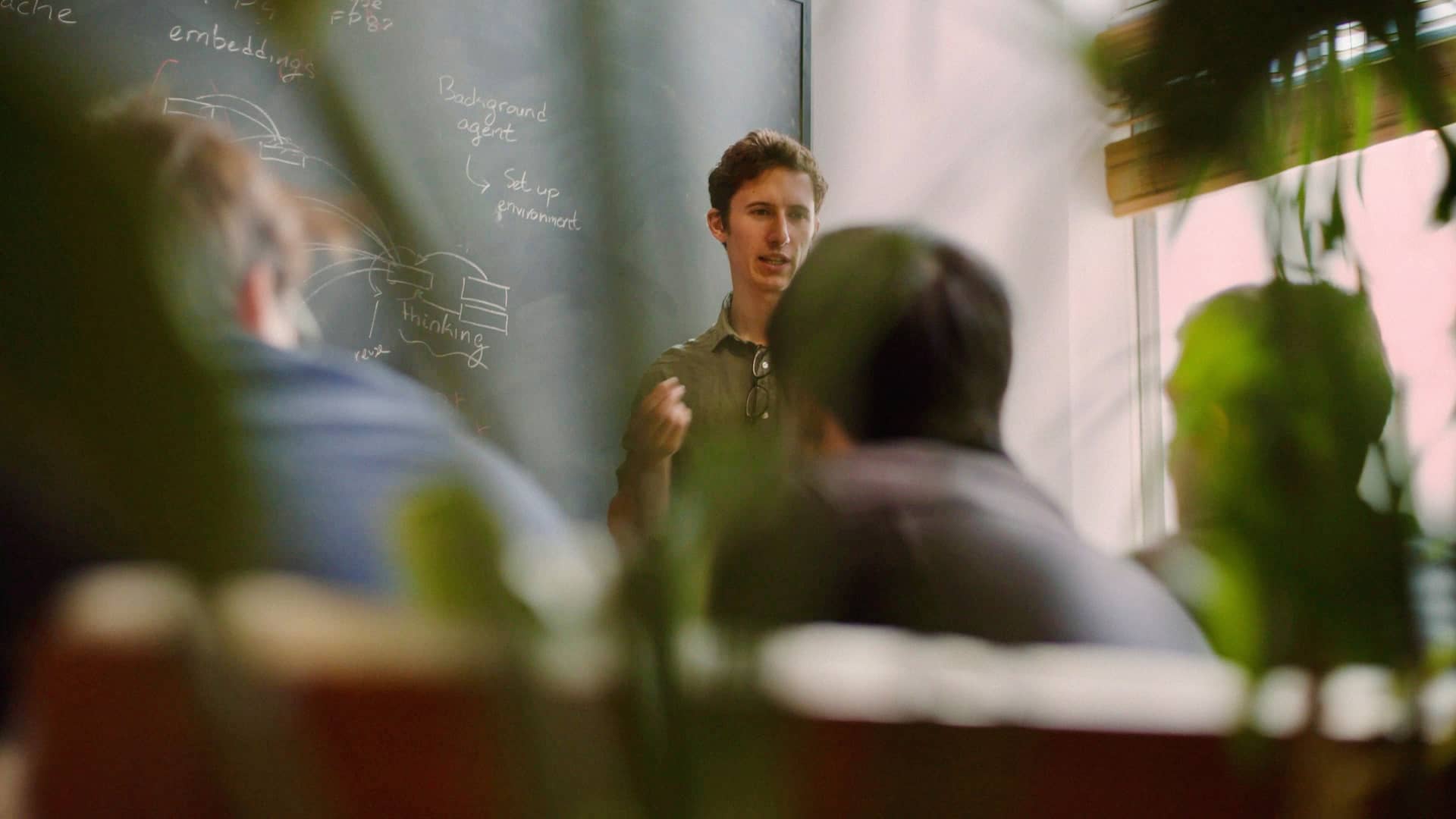 Engineers at Cursor discussing their work around a whiteboard.