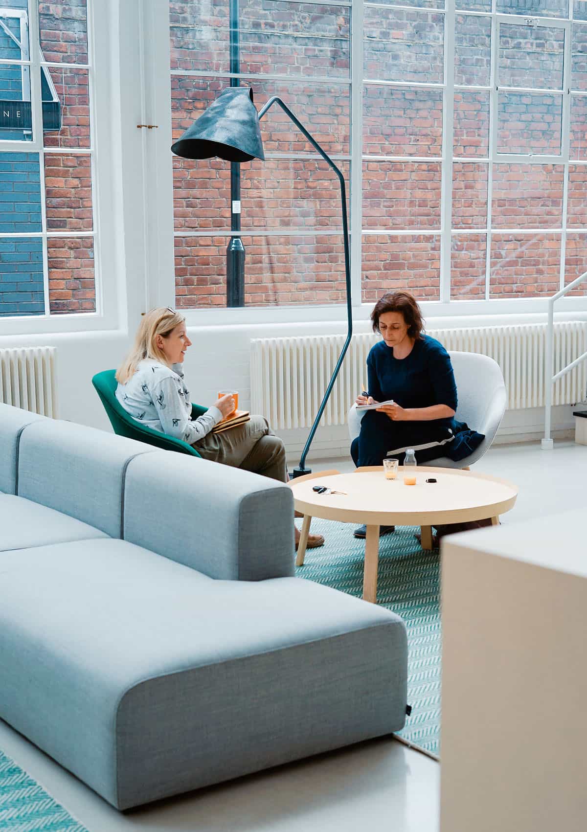Two colleagues discussing their work with notebooks in a shared office.