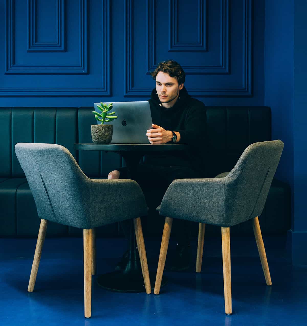 A person concentrating on a laptop at a table.