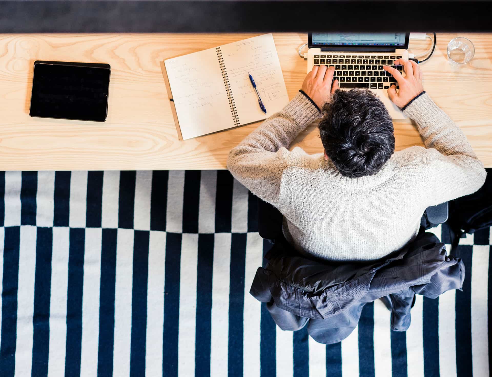 Overhead view of someone working with a laptop and handwritten notes.